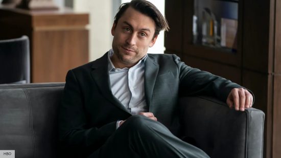 Succession season 4 fired: Roman Roy wearing s suit and smiling in the Waystar offices