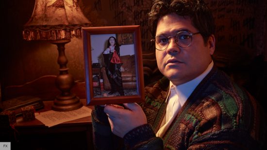 What We Do In the Shadows cast and characters: Harvey Gillen as Guillermo holding up a picture of himself as a kid dressed up as a vampire 