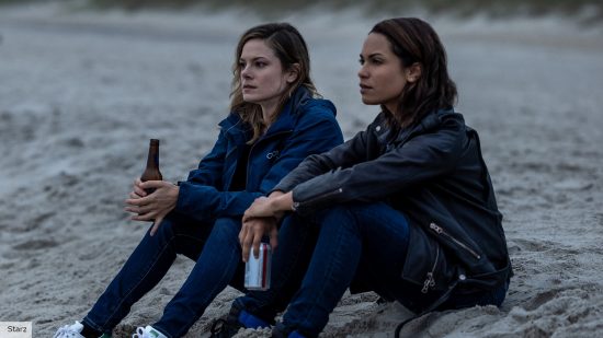 Hightown season 3 release date: Monica Raymund as Jackie Quiñones and Riley Voelkel as Renee Segna sitting on a beach together 