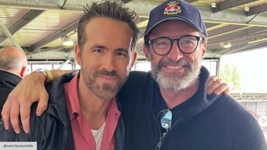 Ryan Reynolds and Hugh Jackman smiling at the camera at a Wrexham AFC game