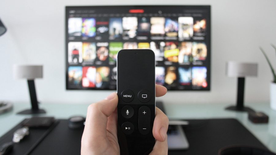 A hand holding a remote in front of a smart tv