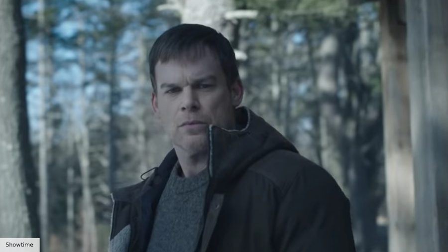 Michael C. Hall's Dexter wearing a black coat over a grey sweater, in a snowy wood, with the sun beaming behind him